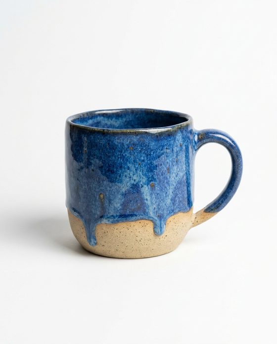 A foto do produto: uma caneca de cerâmica com esmalte azul escorrendo sobre a argila, num fundo branco